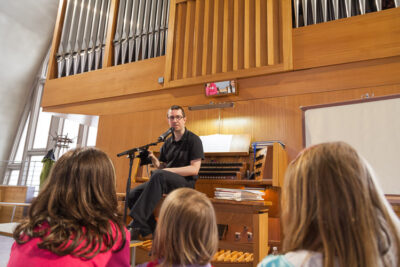 Kinder hören dem Musiker zu, der die Orgel erklärt